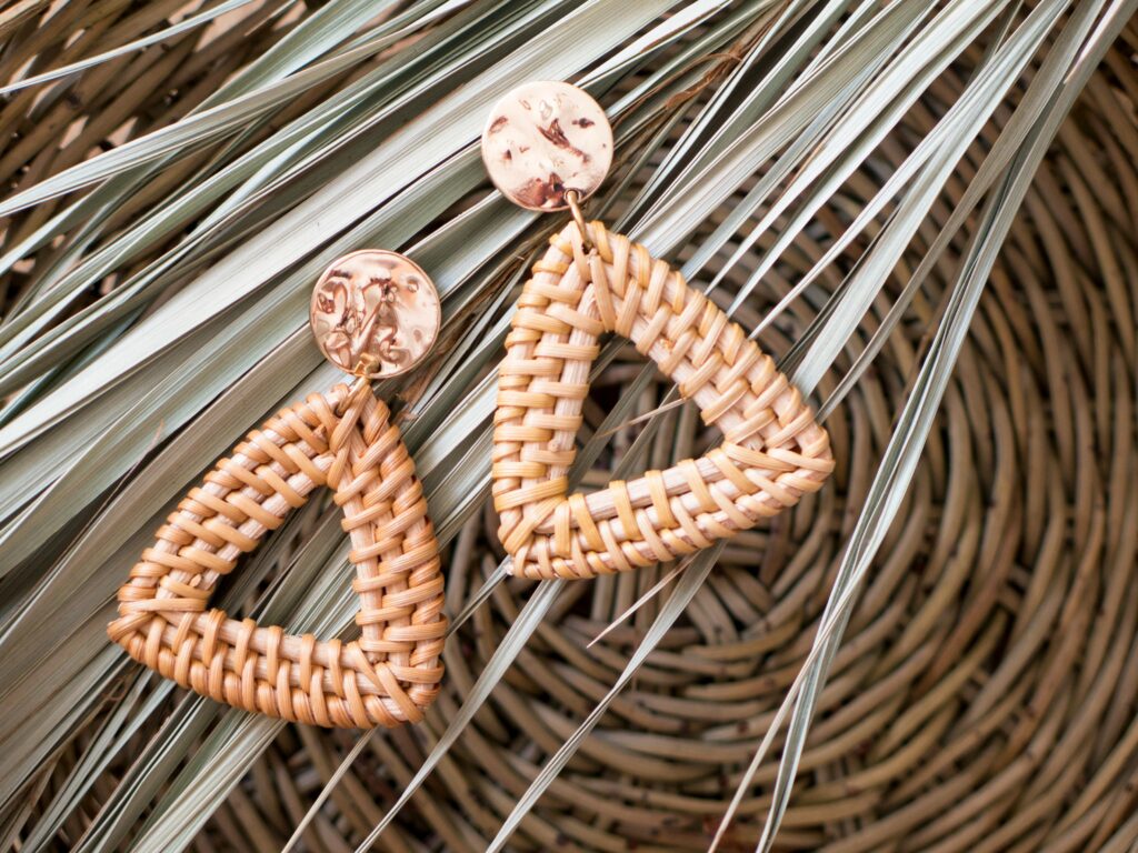 Close-up of geometric rattan earrings on natural palm leaves, showcasing artisan craftsmanship.