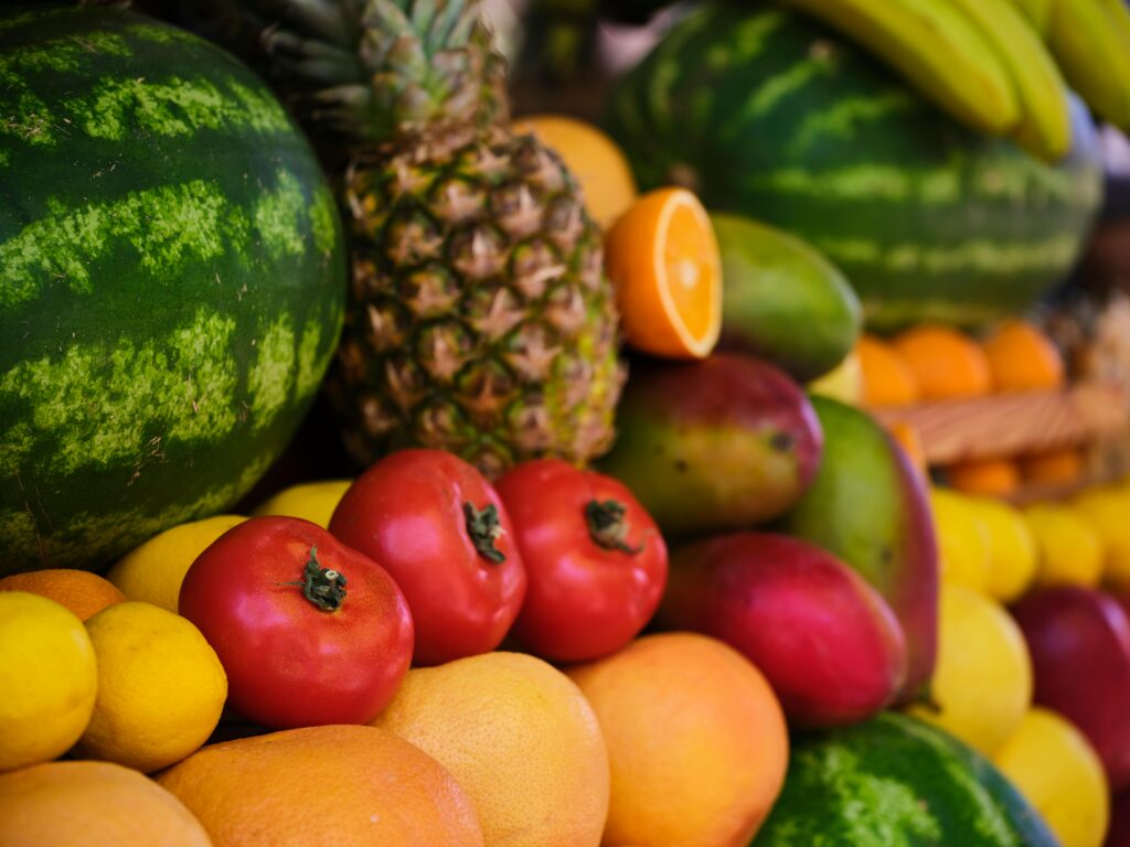 Colorful assortment of fresh tropical fruits including watermelon, pineapple, oranges, and mangoes.