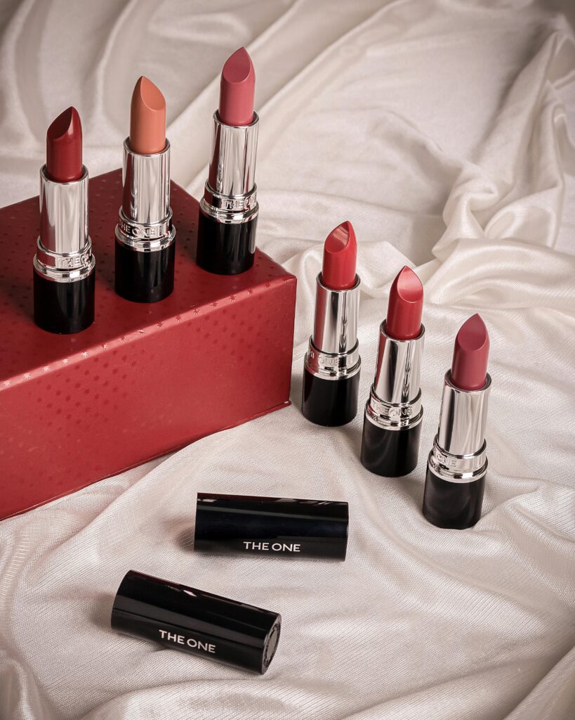 Aesthetic arrangement of vibrant lipsticks on silky fabric background.