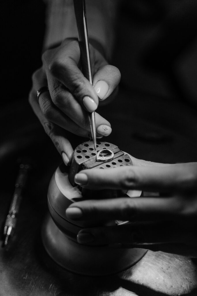 Close-up of a jeweler setting a gemstone in black and white. Precision craftsmanship.