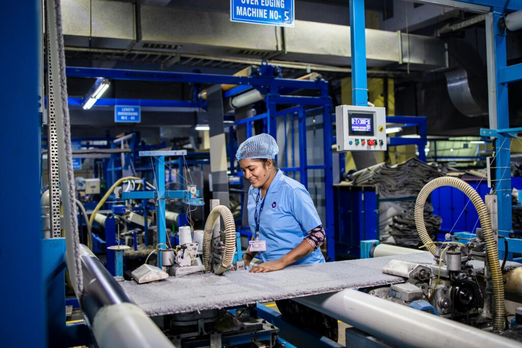 Female textile worker operating machinery in an Indian factory, showcasing industrial production.